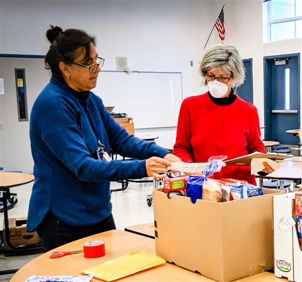  School counselor goes over delivery schedule with volunteer, with food boxes in front of them